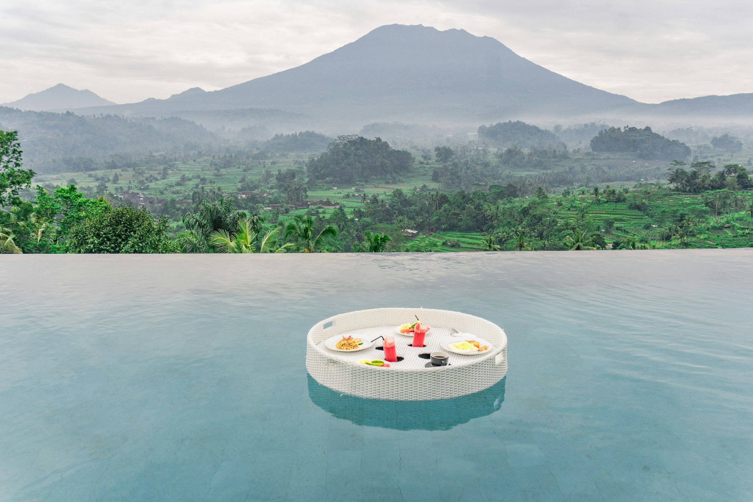Floating breakfast in an infinity pool overlooking rice terraces and Mount Agung, Bali